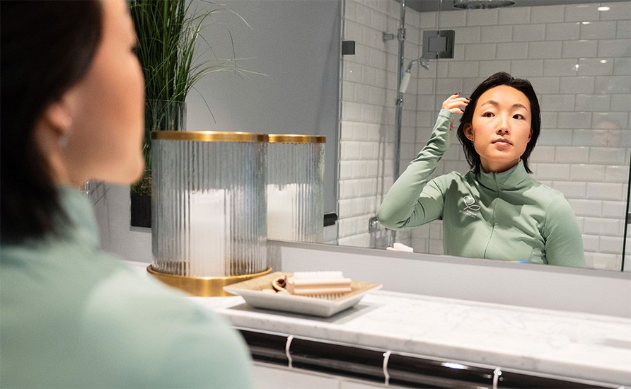 Kvinna som speglar sitt ansikte i ett badrum.