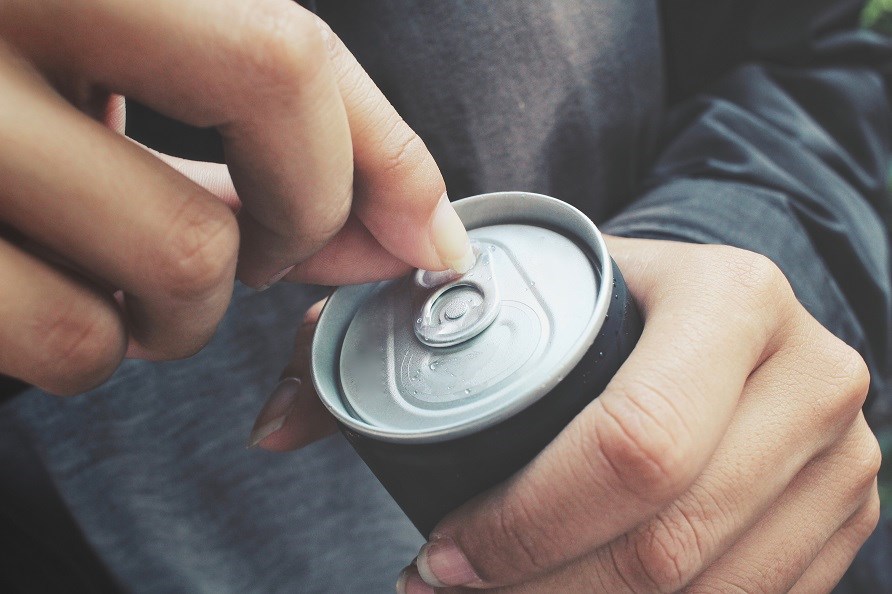 Bild p� tv� h�nder som h�ller i en aluminiumburk.