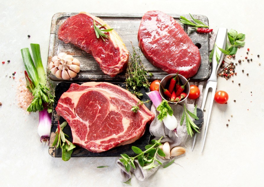 R�a biffar upplagda p� en sk�rbr�da med tillbeh�r runt omkring.