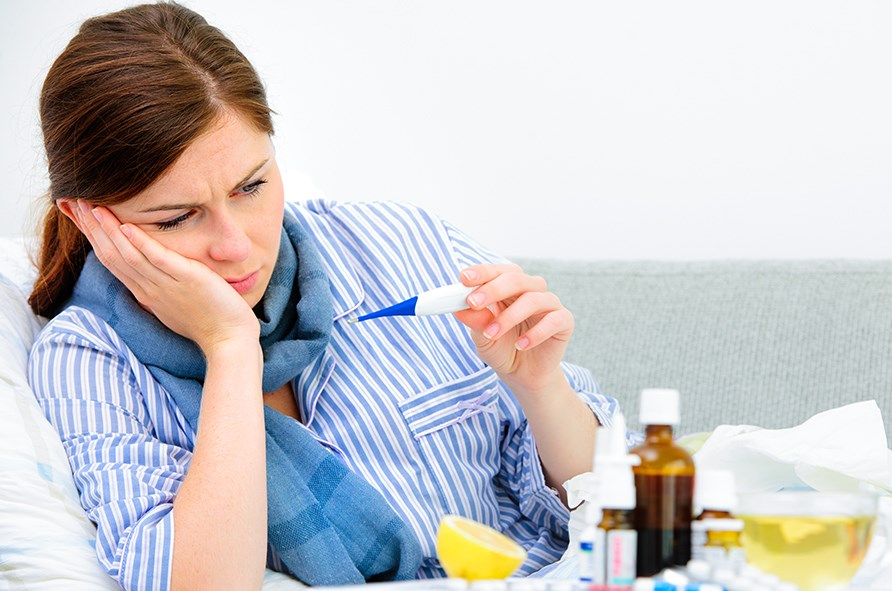 Kvinna med febertermometer i handen. 