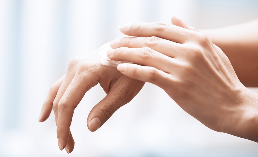 Hnder som smrjer in en handkrm p huden.