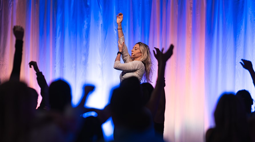 Johanna Hector str p en scen framfr publik och hller upp ena armen med sin andra arm, publiken gr likadant. 