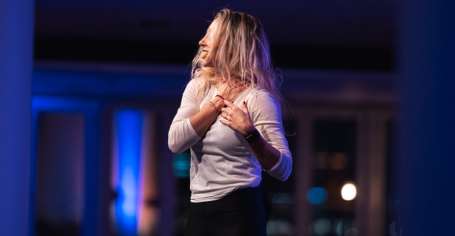 Johanna Hector str framfr en publik som inte syns i bild och hller sin hand ver ena nyckelbenet.