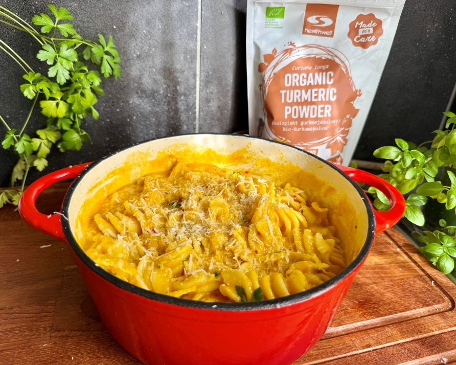 Kalorismarts  kycklinggryta i en rd, stor gryta, p en kksbnk av tr, och frpackning med Healthwell Gurkmeja Pulver EKO.