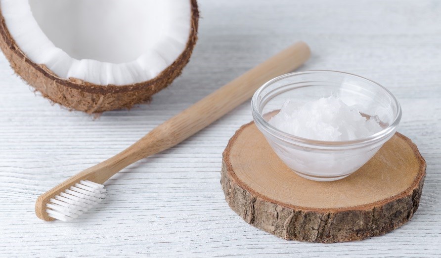 Kokosolja i en glasskål, en tandborste tillsammans med en halv kokosnöt. Kokosolja i en glasskål, en tandborste tillsammans med en halv kokosnöt.