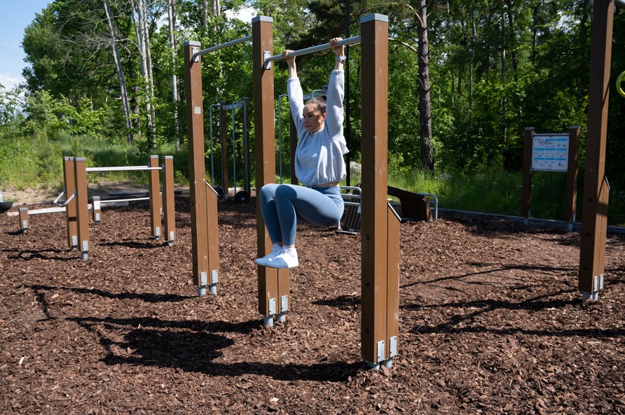 Kvinna utför övningen hängande benlyft Kvinna utför övningen hängande benlyft