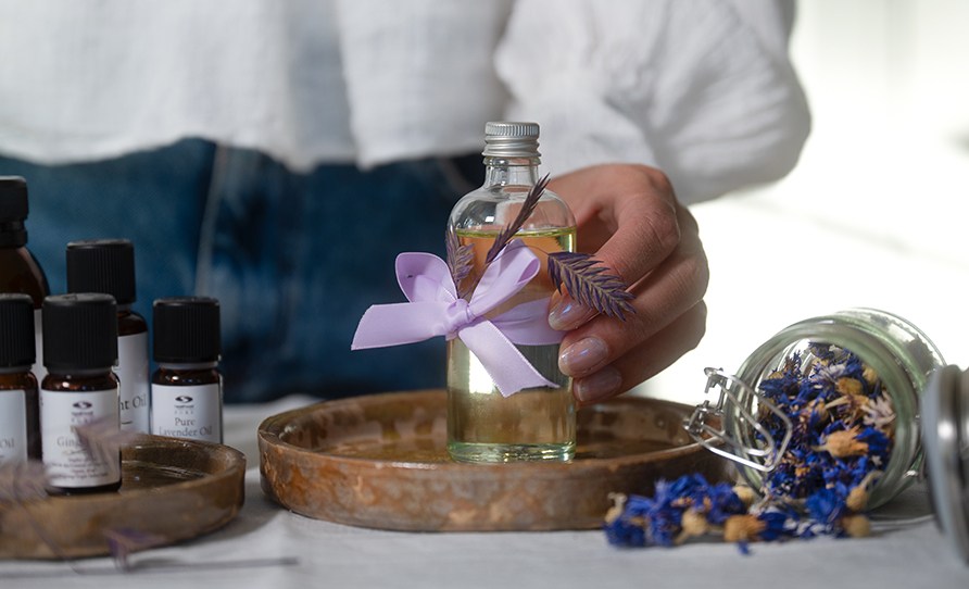 Kvinna som greppar en glasflaska med hemmagjord massage olja i.