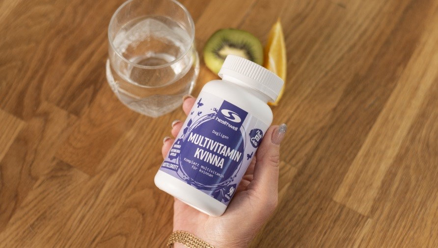 Multivitamin kvinna kapsel med vitaminer och mineraler med ett glas vatten.
