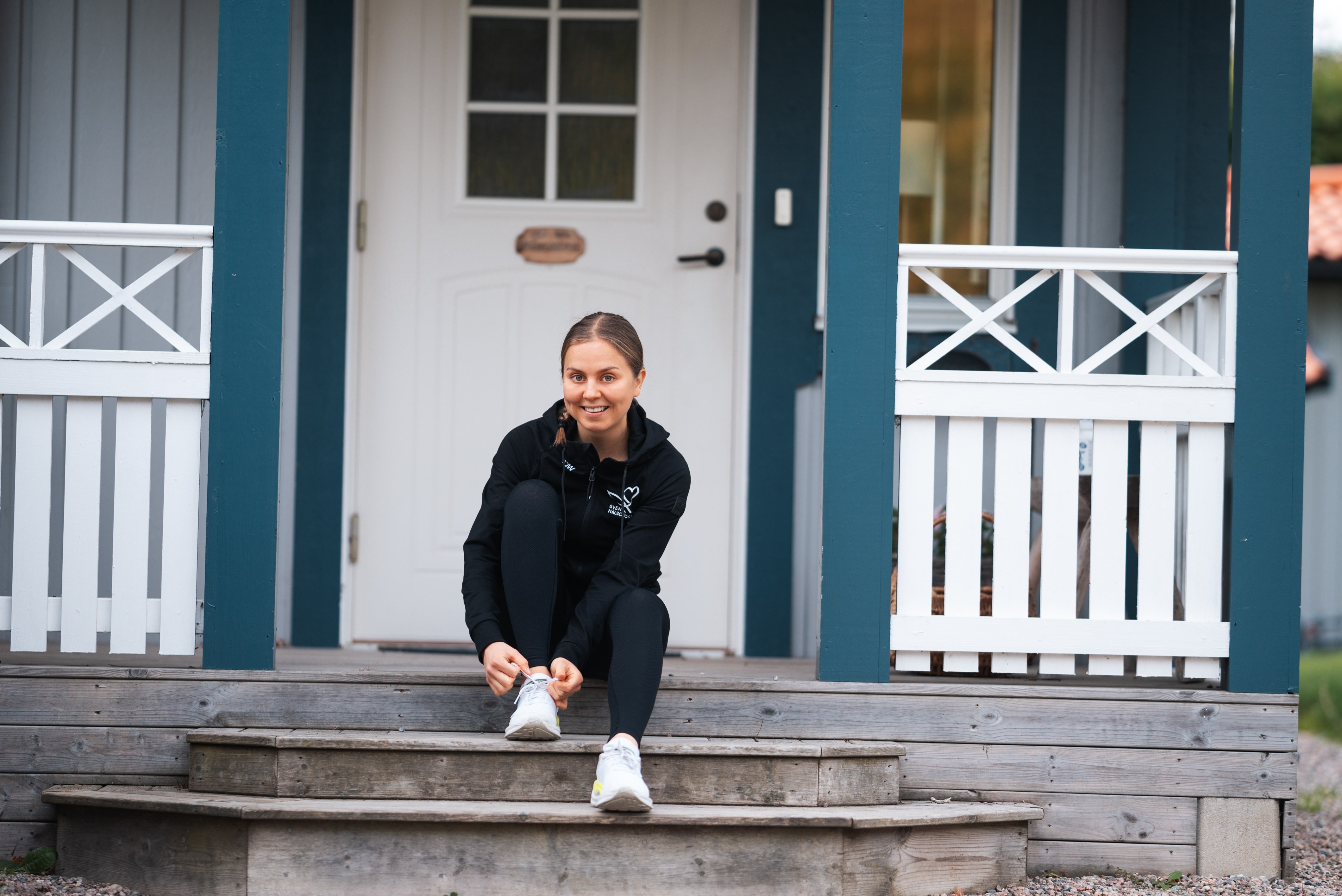 Josefine snrar p sig joggingskorna sittandes p en trappa som leder upp till en villa.