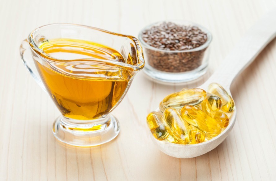 Linfröolja i en kanna, kapslar med linfröolja och linfrön i en skål.