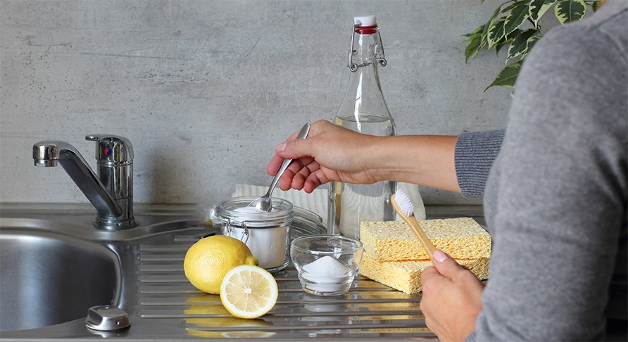 Bild p en arm som hller en tsk i en genomskinlig skl med bikarbonat, p en diskbnk.