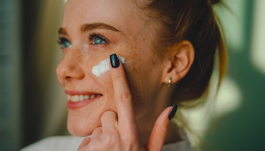 Kvinna smrjer in ansiktet med ansiktskrm.